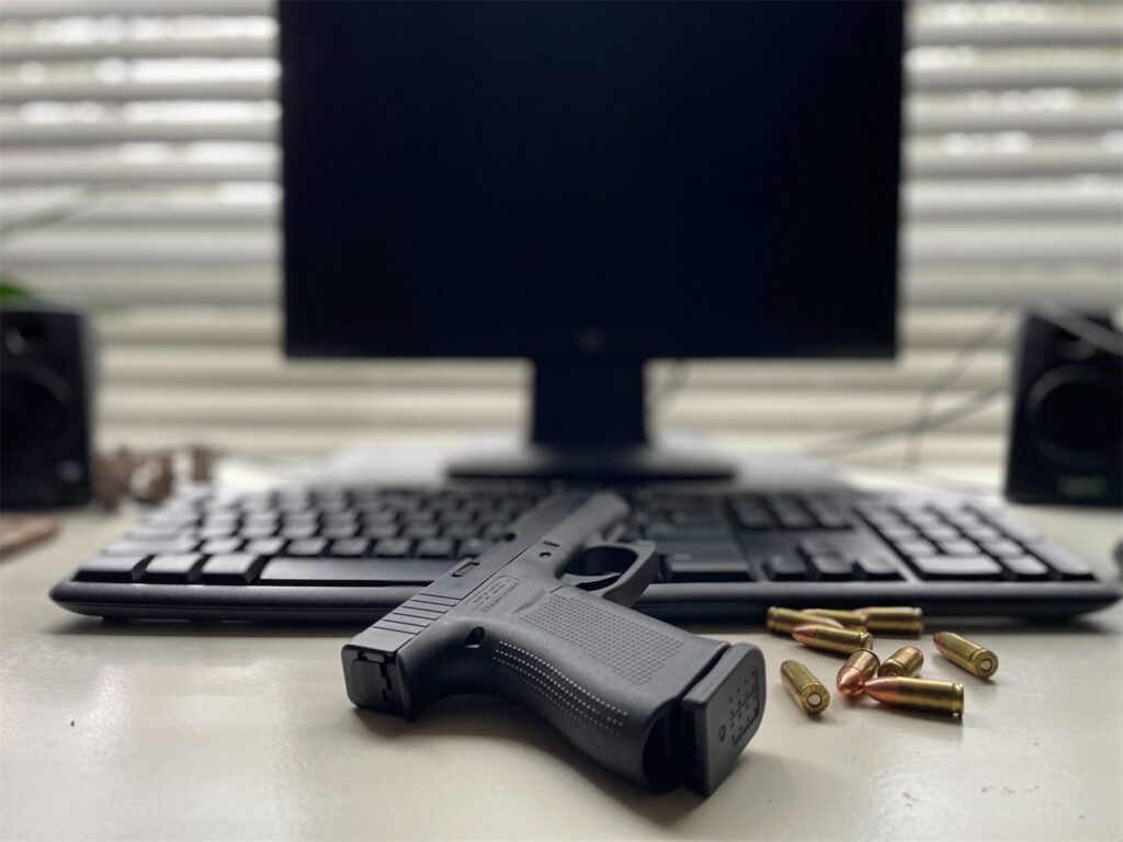 Handgun and ammunition beside a laptop, representing the online License to Carry course