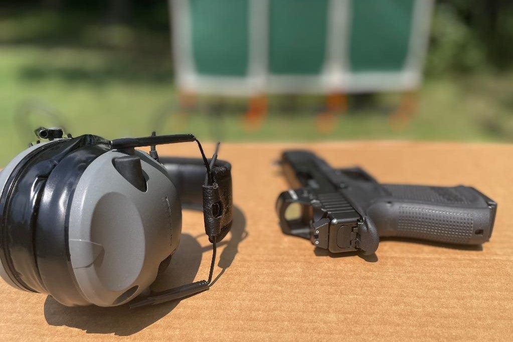 Handgun with a red dot optic laid out on a shooting bench