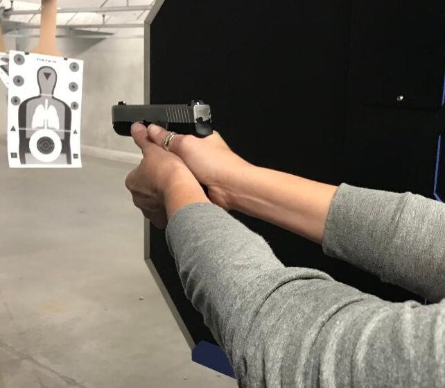 Instructor guiding a student's grip on a handgun during private pistol training