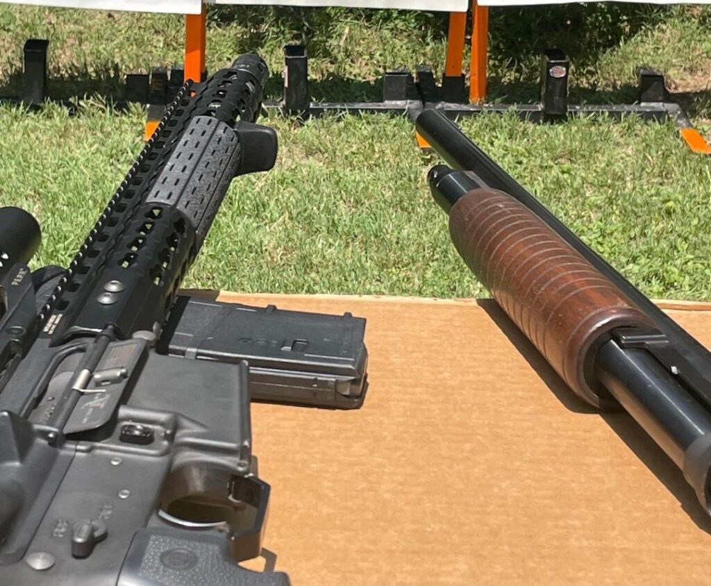 AR-15 rifle and pump shotgun crossed on a shooting bench at the range